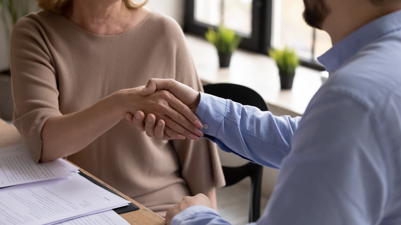 Young executive shaking hand of successful mature smiling woman concept.